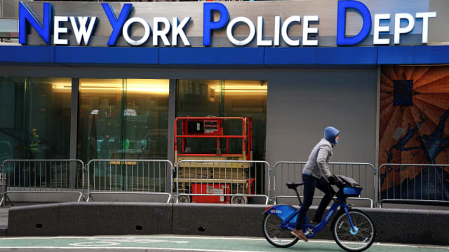 A bicyclist rides past a New York Police Department precinct.