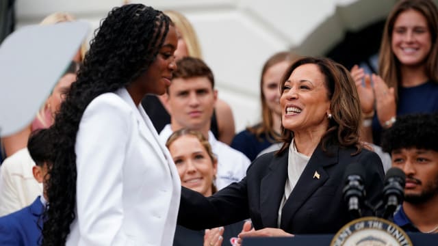 Vice President Kamala Harris standing at a podium with a student. 