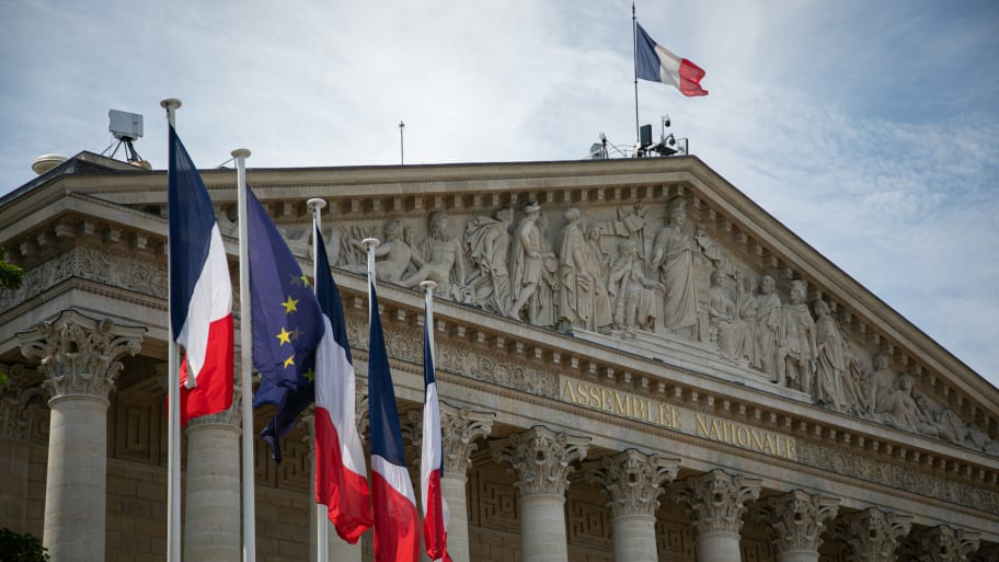 French flags are seen by a side of the facade of the National Assembly