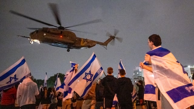 People wave flags and cheer as a second helicopter with Israeli hostages released earlier by Hamas lands
