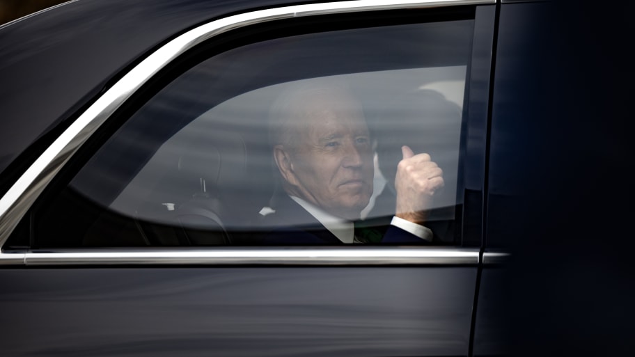 President Joe Biden gives a thumbs-up in a car.
