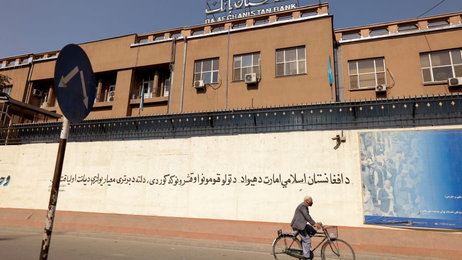 A man rides a bike in front of the Bank of Afghanistan in Kabul, Afghanistan.