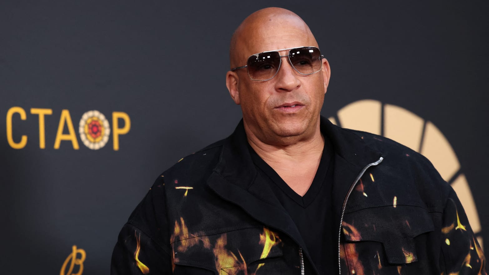 Vin Diesel, wearing sunglasses, stares forward as he’s photographed outside an event in Los Angeles.