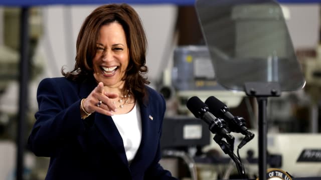 Kamala Harris laughs and points into the crowd at a campaign event.