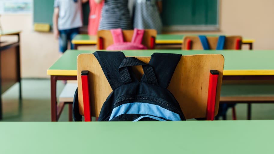 A backpack sits in the chair of an elementary classroom.
