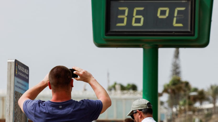 A tourist photographs a thermometer during a hot spring day