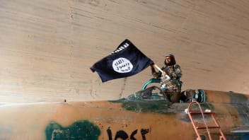 Islamic State fighter (ISIS; ISIL) waving a flag while standing on captured government fighter jet in Raqqa, Syria, 2015.