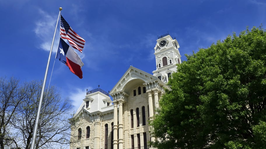 American and Texas flags fly in front of the Hill County courthouse in Hillsboro Texas. 