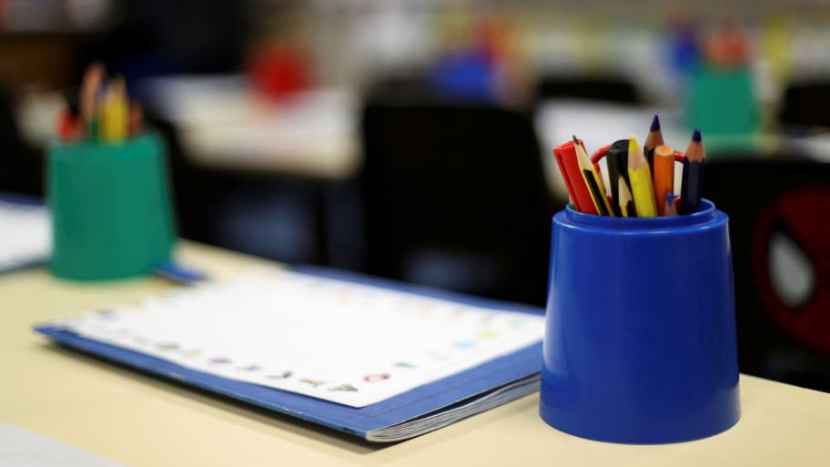 A teacher's desk with a cup of pencils