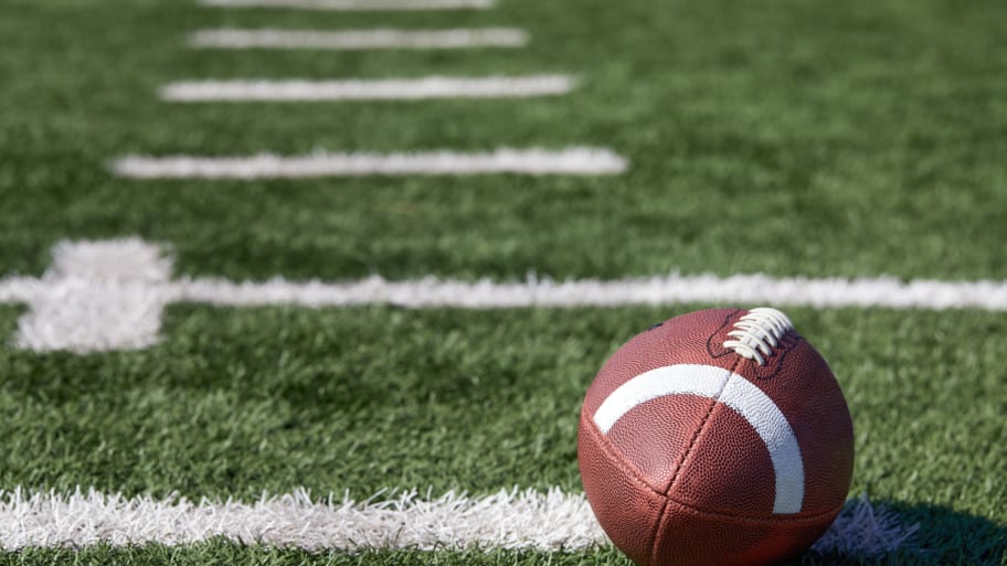 A football lies on a field. A longtime photographer for a high school football team in Wichita, Kansas, has died after players collided with her during a game.