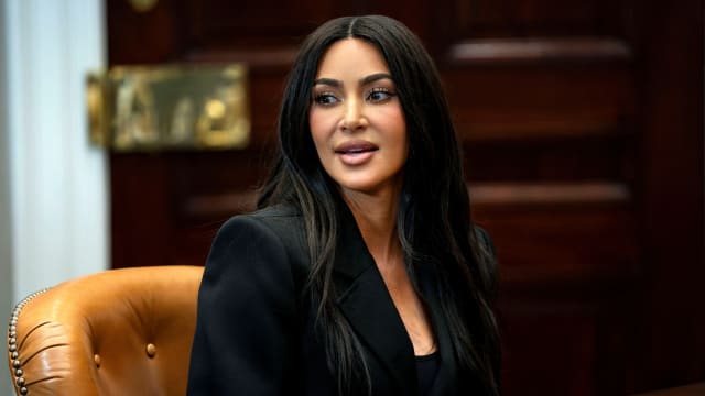Kim Kardashian, wearing black, speaks at a meeting table.