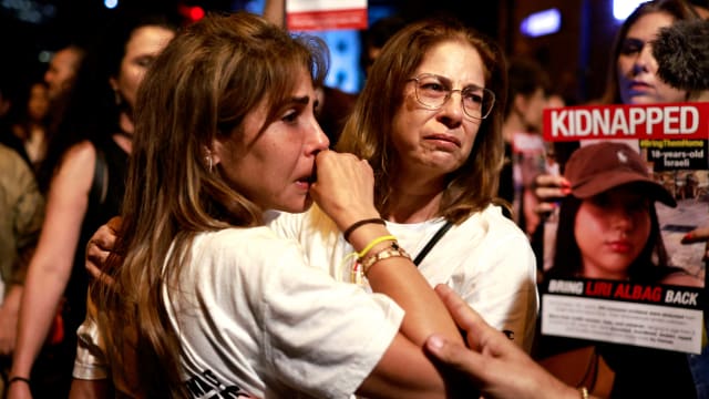 People in Tel Aviv cry and hold signs of hostages held by Hamas in Gaza