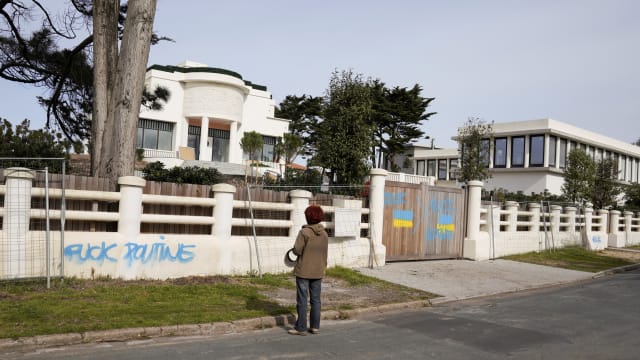A person looks at anti-Putin graffiti and painted Ukrainian flags at a villa believed to belong to Lyudmila Ocheretnaya, former wife of Russian president Vladimir Putin, in Anglet, France, March 1, 2022. 
