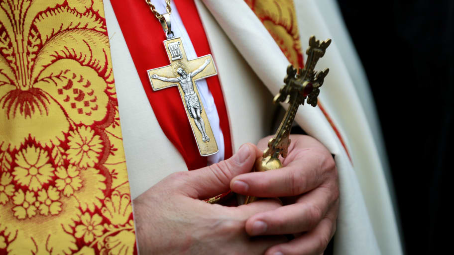 A priest holds a cross.