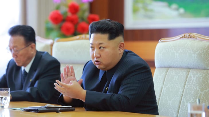 North Korean leader Kim Jong Un sitting down at a table.