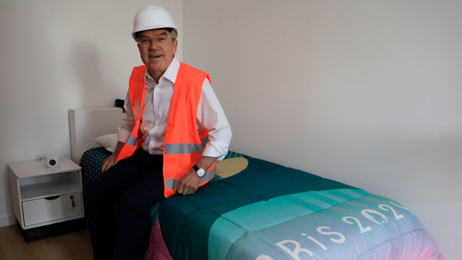 President of the International Olympic Committee (IOC) Thomas Bach sits on a bed as he visits the Athletes village of the 2024 Summer Olympics.