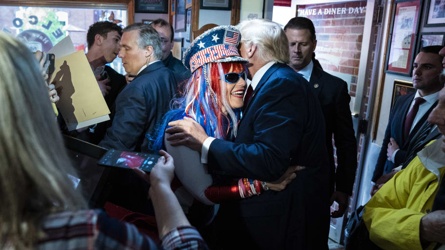 Former President Donald Trump greets Micki Larson-Olson while visiting the Red Arrow Diner after a campaign rally on Thursday, April 27, 2023, in Manchester, NH.