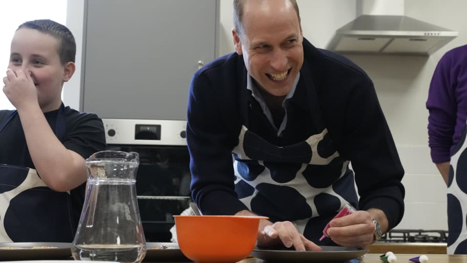 Prince William, Prince Of Wales smiles as he looks up while decorating biscuits during his visit to WEST, a new OnSide Youth Zone WEST on March 14, 2024 in London, England.