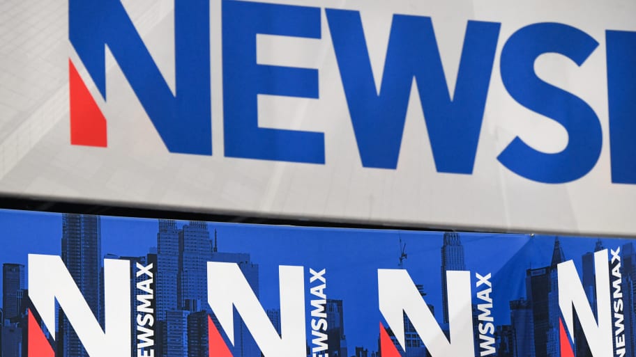 Signage for the Newsmax conservative television broadcasting network is displayed at a broadcast TV booth at the National Rifle Association (NRA) annual meeting 