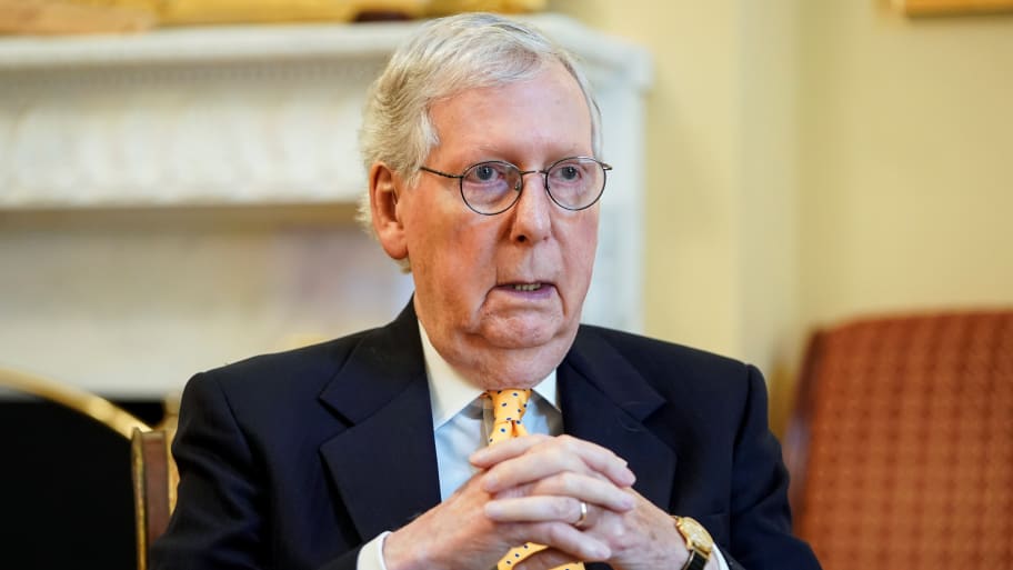 Mitch McConnell clasps his hands as he speaks in a building on Capitol Hill