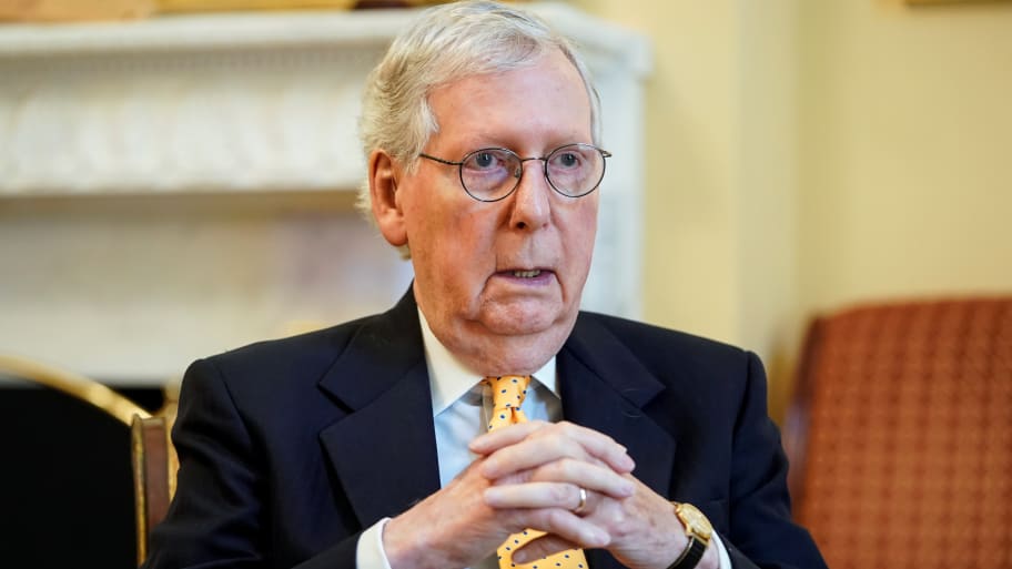 Mitch McConnell clasps his hands while sitting inside a building on Capitol Hill