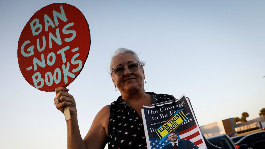 A woman holds a sign during a gathering outside a Books-a-Million bookstore where Florida Gov. Ron DeSantis is expected to sign copies of his book “The Courage to Be Free” in Leesburg, Florida, Feb. 28, 2023.