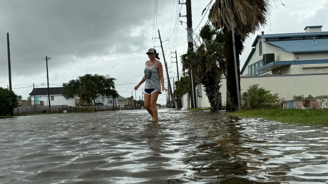 Allison Crane walks out of her flooded neighborhood after Hurricane Beryl passed in Galveston, Texas.