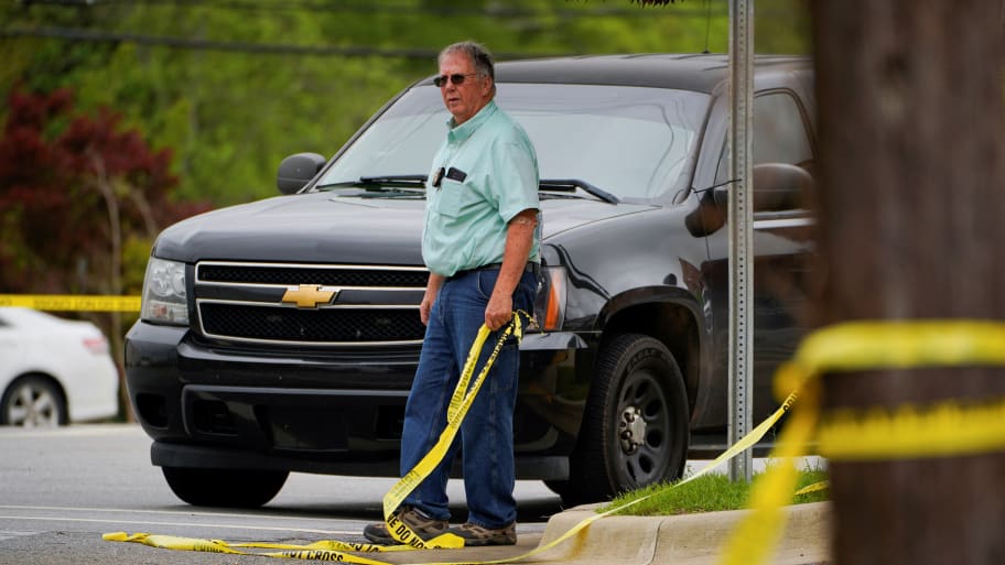 A law enforcement officer holds a piece of crime scene tape, a day after a shooting at a teenager's birthday party in a dance studio in Dadeville, Alabama.