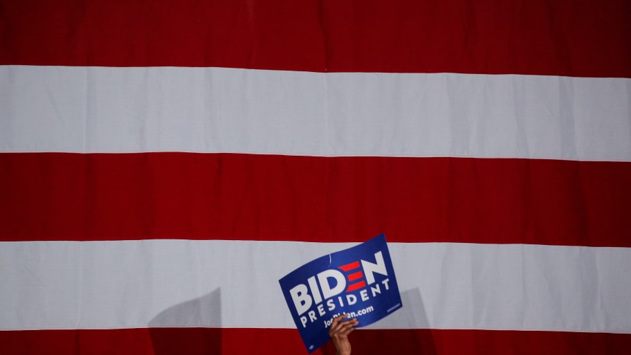 A sign that reads “Biden President” against an American flag backdrop.