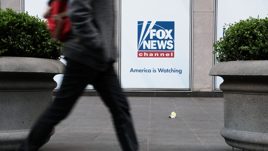 Someone walking in front of the Fox News headquarters. 