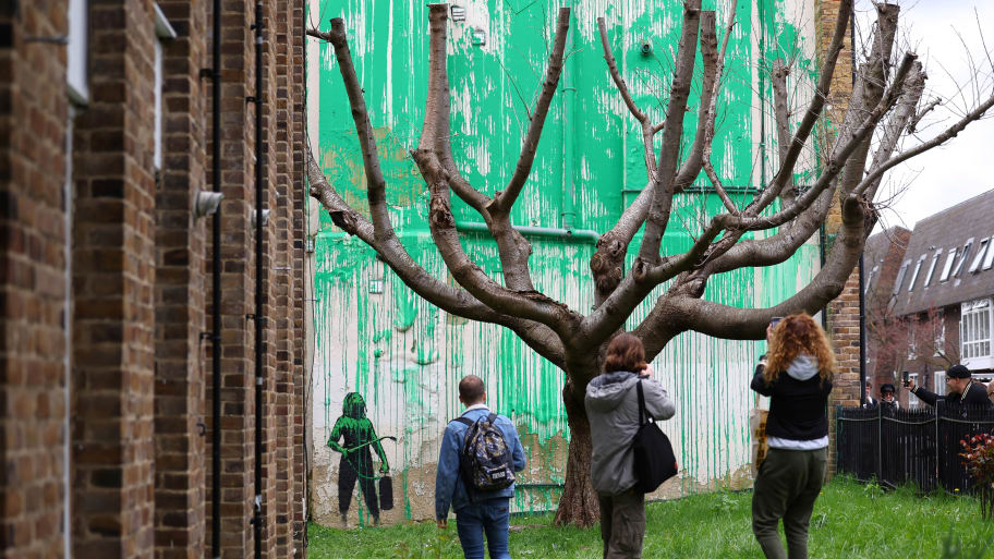 People view the latest mural by Banksy, a spray-painted tree, in London.