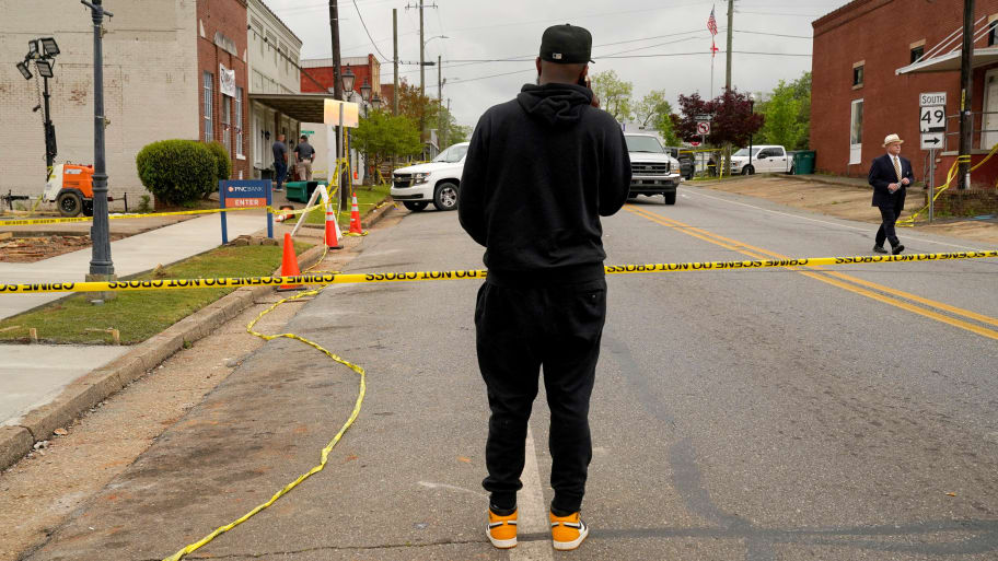 A man speaks on the phone while standing at the edge of the crime scene a day after a shooting at a teenager’s birthday party in a dance studio, in Dadeville, Alabama, April 16, 2023. 