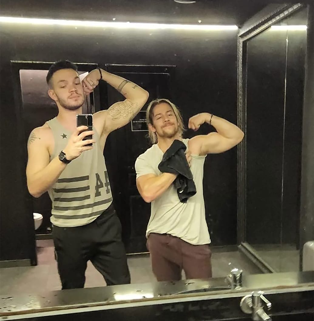 Mor Cohen flexes his bicep in the mirror with a friend