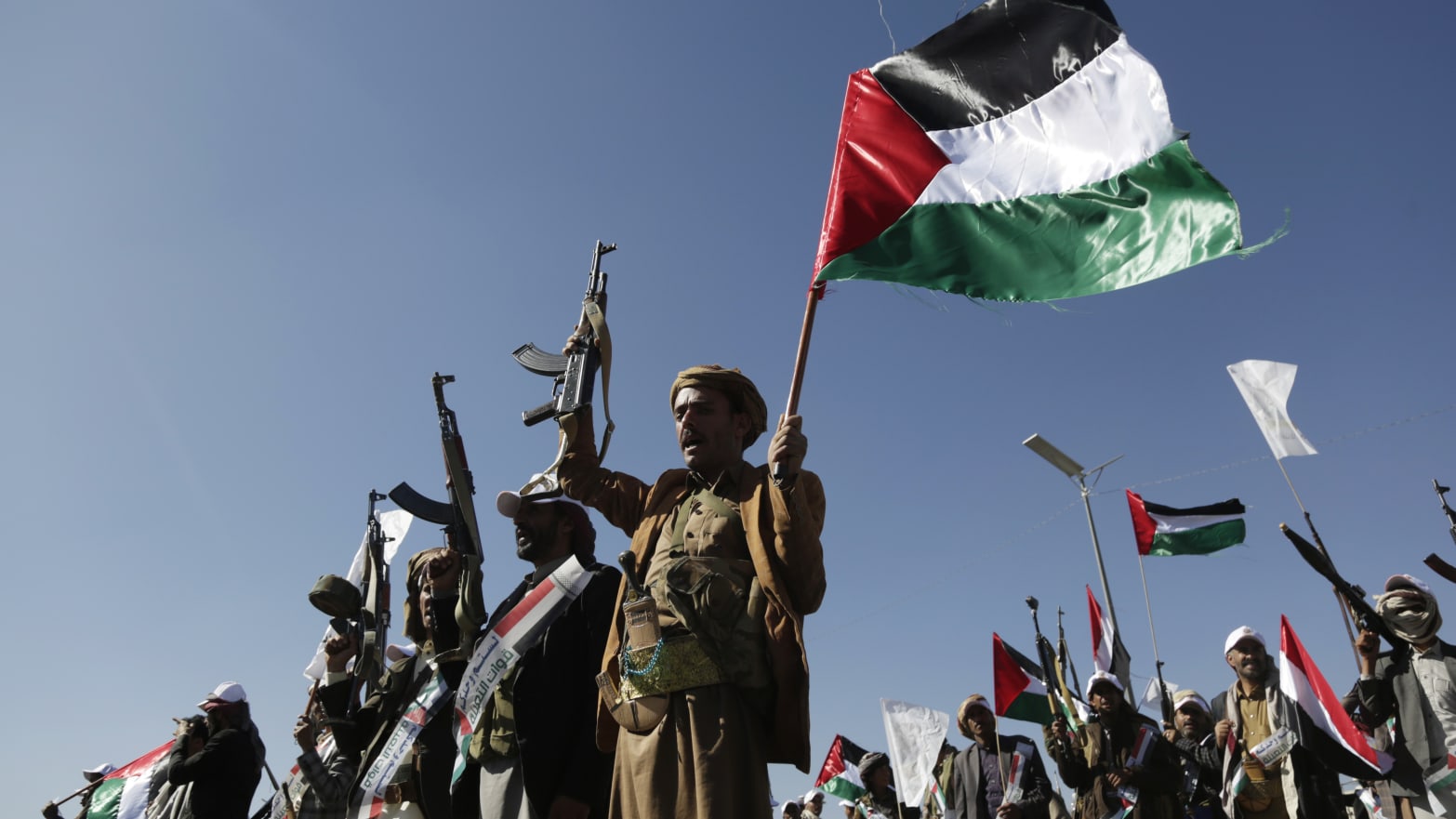 Yemenis recently militarily trained by the Houthi movement holding up their guns and Palestinian flag chant slogans