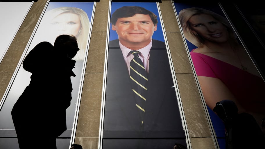 People pass by a promo of Fox News host Tucker Carlson on the News Corporation building in New York.