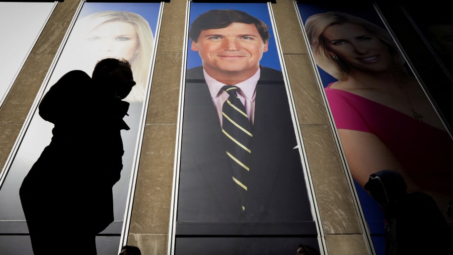 People pass by a promo of Fox News host Tucker Carlson on the News Corporation building in New York.