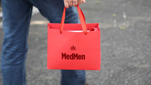 A photo of a MedMen customer carrying a red MedMen shopping bag.