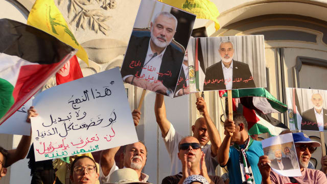 Demonstrators carry pictures of Hamas leader Ismail Haniyeh