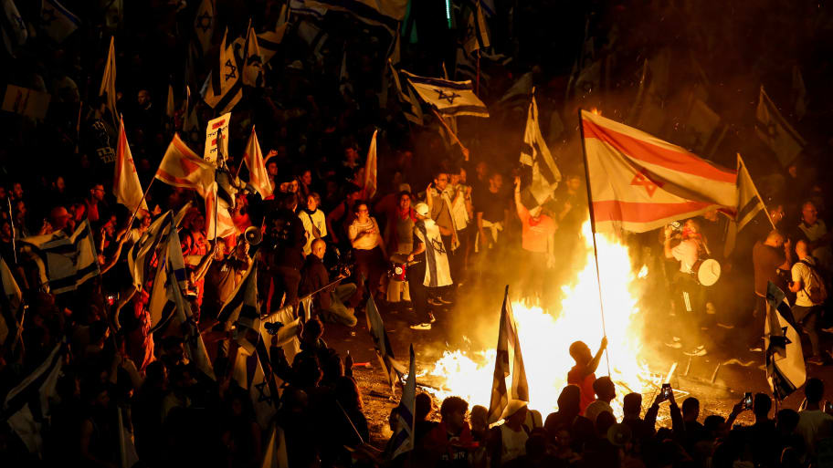 Fire burns as people attend a demonstration after Israeli Prime Minister Benjamin Netanyahu dismissed the defense minister and his nationalist coalition government presses on with its judicial overhaul, in Tel Aviv, Israel, March 27, 2023. 