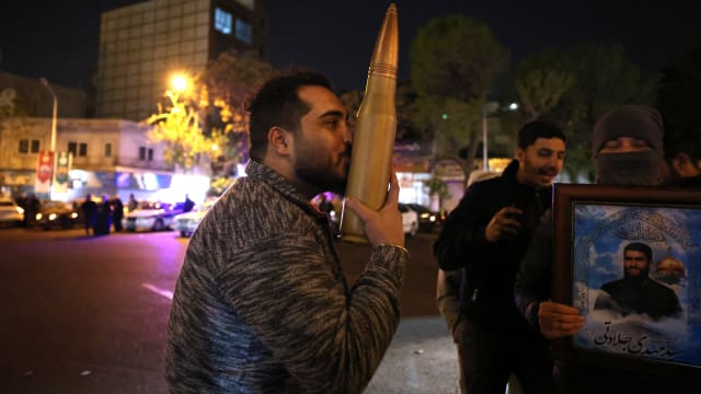 A demonstrator kisses a bullet shell replica as others gather at Palestine Square in Tehran on April 14, 2024, after Iran launched a drone and missile attack on Israel.