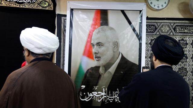 People mourn near a photo of Ismail Haniyeh.