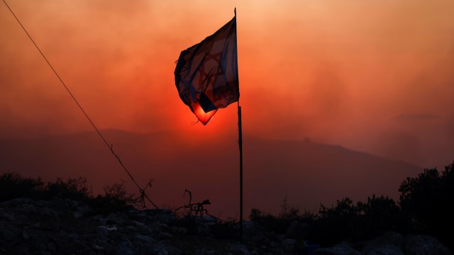 Distressed Israeli flag with red haze in the background