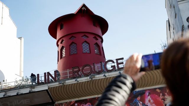 People take pictures of the landmark red windmill atop the Moulin Rouge, Paris' most famous cabaret club, after its sails fell off during the night in Paris, France, April 25, 2024.