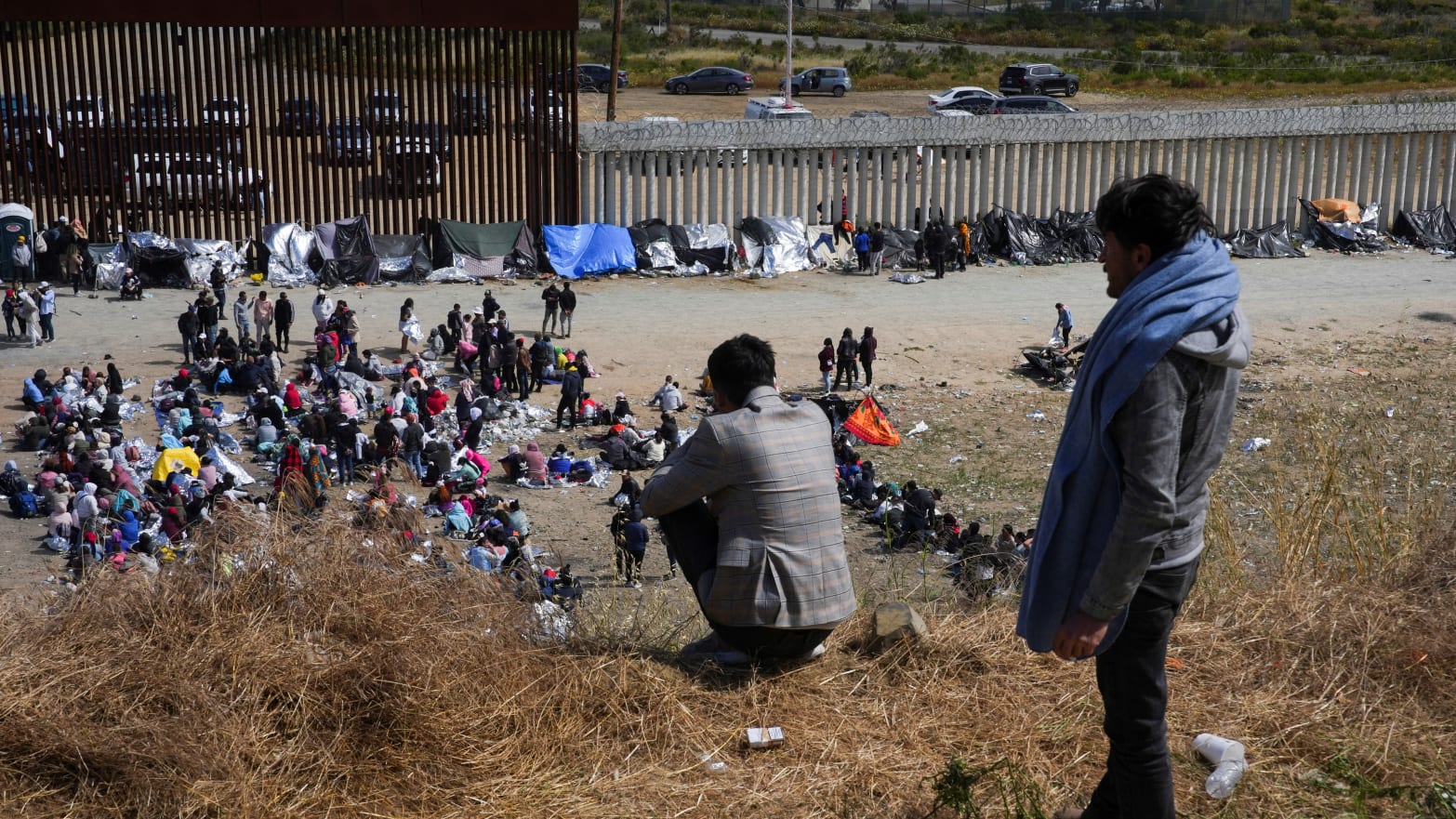Migrants gather between the primary and secondary fences of the U.S.-Mexico border 