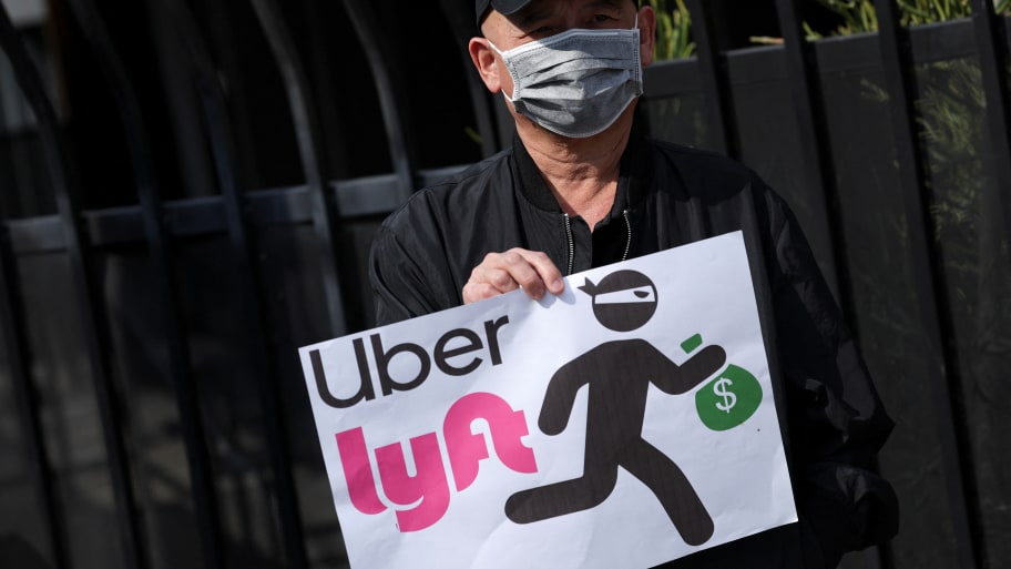 A person holds a placard criticizing Uber and Lyft. 