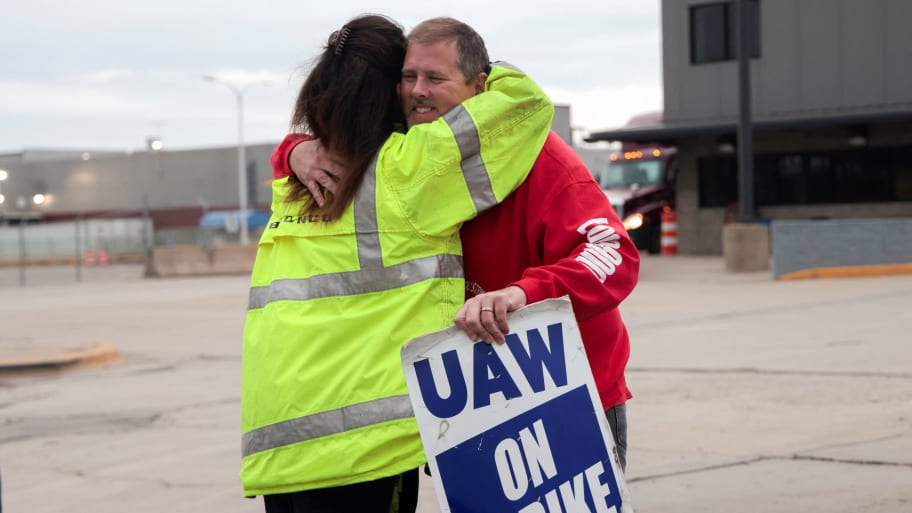 Striking United Auto Workers union members embrace at the end of their picket shift