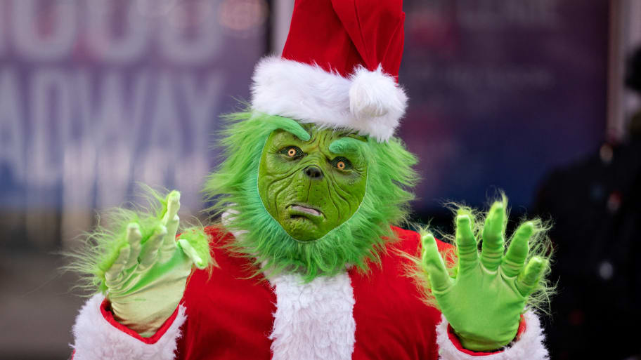 A person dressed as the Grinch in Times Square poses for photos in New York City, Dec. 9, 2022.