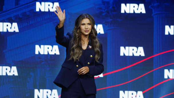 Kristi Noem waves to audience members at the 2023 National Rifle Association convention.