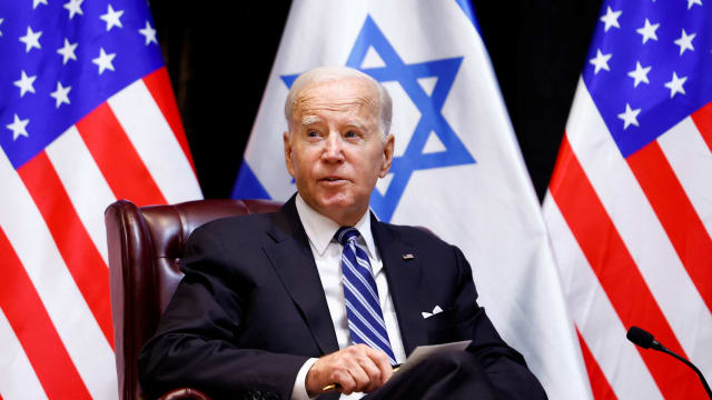 President Joe Biden sits in front of Israeli and American flags.