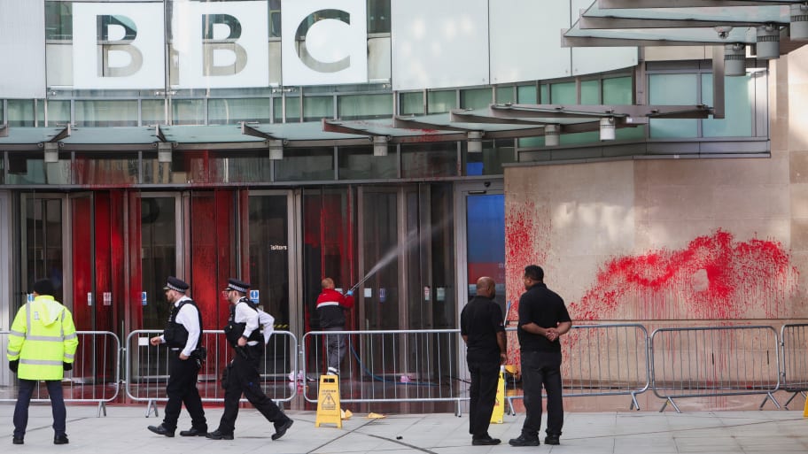 Police officers walk outside the BBC building, near where a march for a protest in solidarity with Palestinians, covered in red paint.